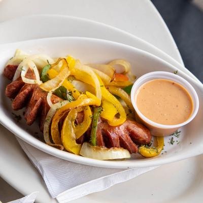 Alligator sausage with grilled onions and peppers, and a white tiger sauce