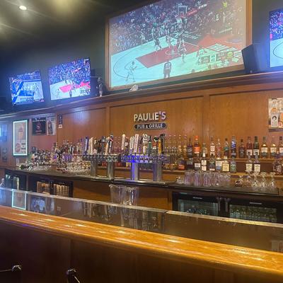 Bar area with liquor bottles, beer taps, and TVs showing basketball.