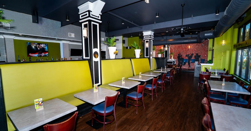 Interior of a restaurant with green booths, gray tables, and red chairs