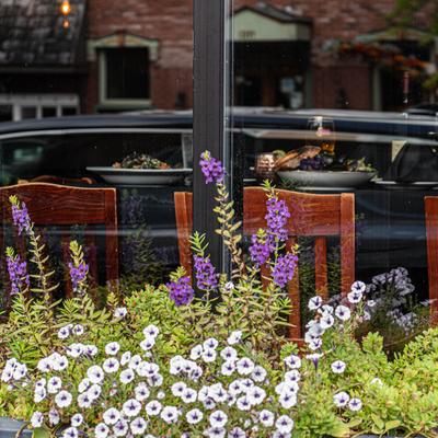 Exterior restaurant window with flowers in the foreground and a table with food inside