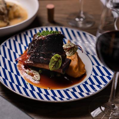 Prime Braised Short Ribs served with a glass of red wine.