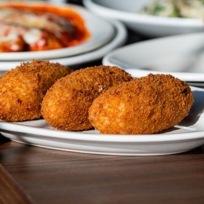 Fried balls of rice with tomato sauce and cheese.