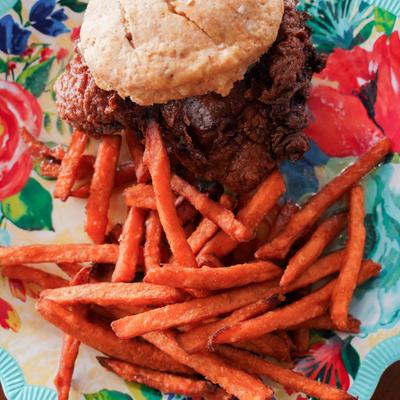 Fried chicken biscuit sandwich with sweet heat mustard sauce, accompanied by sweet potato fries.