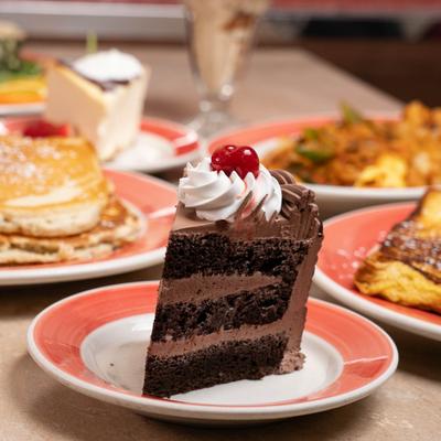 A slice of chocolate cake topped with whipped cream and a cherry.