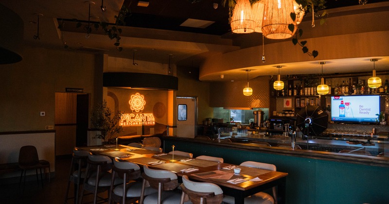 Interior of "Picanta Mexican Kitchen" with warm lighting and decorated dining and bar areas.