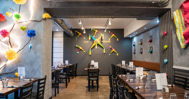 Diner area, tables, chairs, booths, pinata's on the wall, wide view