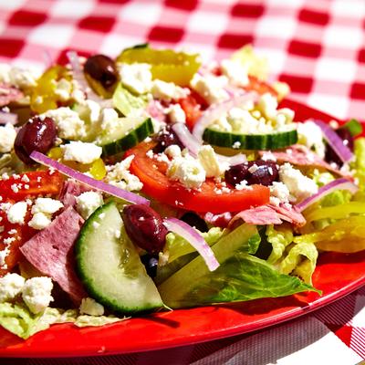 Close up view of a salad with cucumbers, feta, red onion, olives.