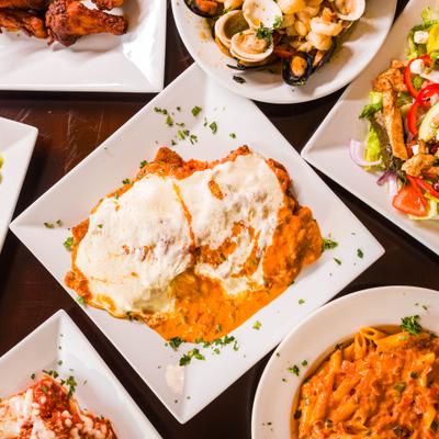 Pasta in creamy tomato sauce on center plate, surrounded by assorted food dishes.