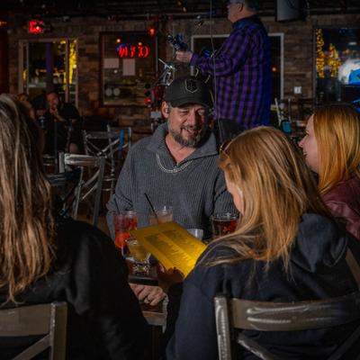 A group of customers sitting at a table with drinks during a music performance.
