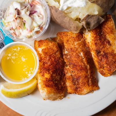 Baked fish, baked potato, sour cream, coleslaw, butter, rye toast.