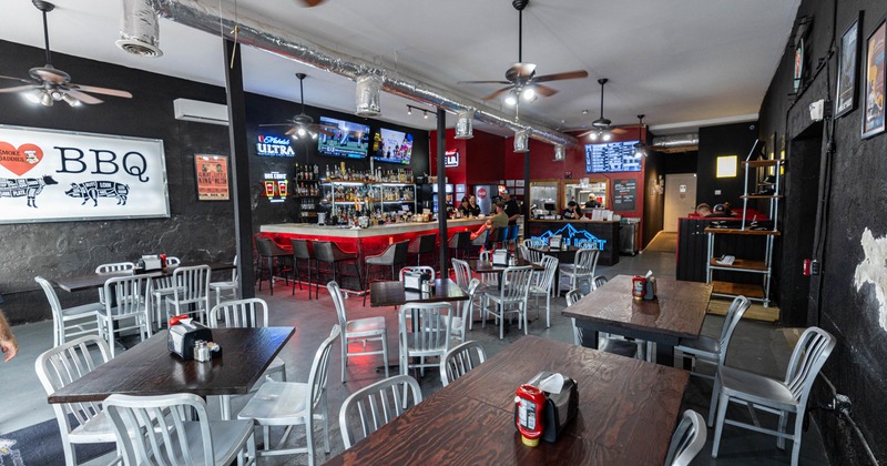 Interior, tables and metal chairs, a red-and-black bar, televisions, menus