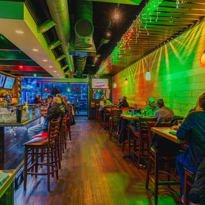 Interior view of lively bar and restaurant with patrons seated at the bar and dining tables.