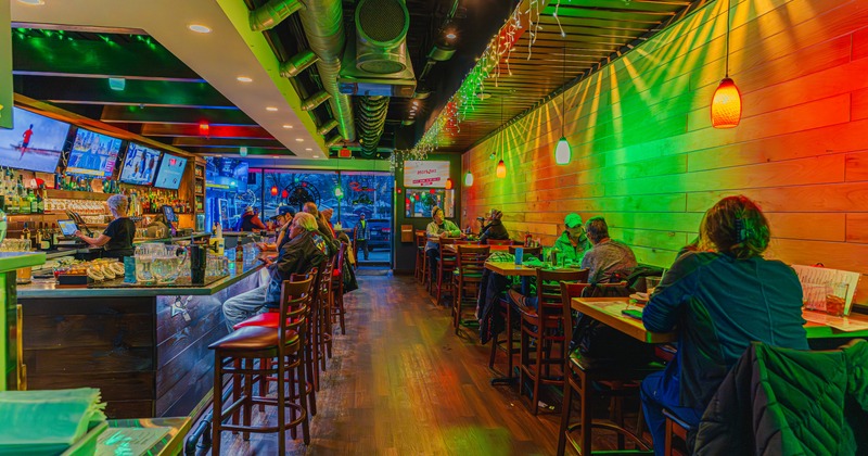 Seating area with tables and chairs, a bar and colorful lights