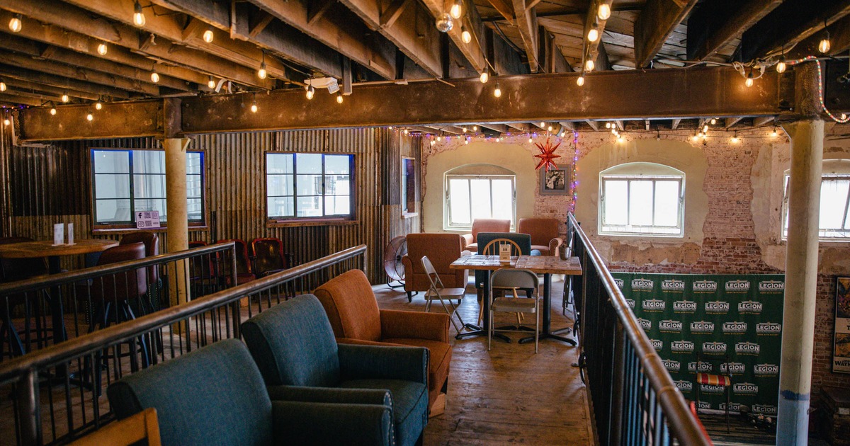 A cozy interior space with wooden beams, string lights, and a mix of seating