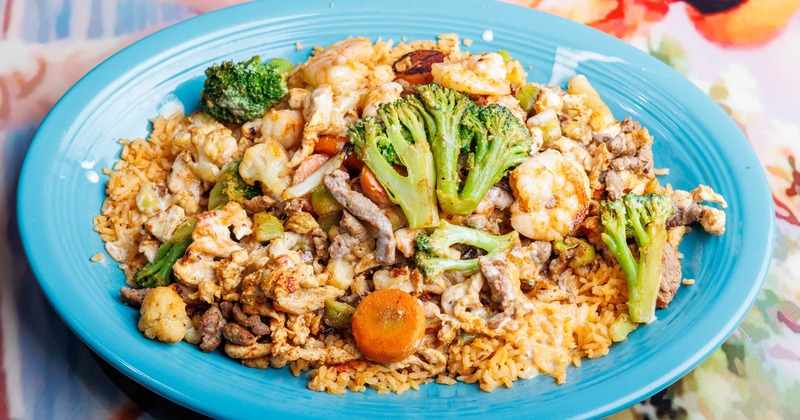 Grilled chicken, steak, and shrimp, cooked with sauteed vegetables, rice, and cheese sauce