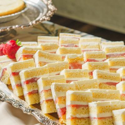 Slices of layered strawberry sponge cake arranged on a silver tray.
