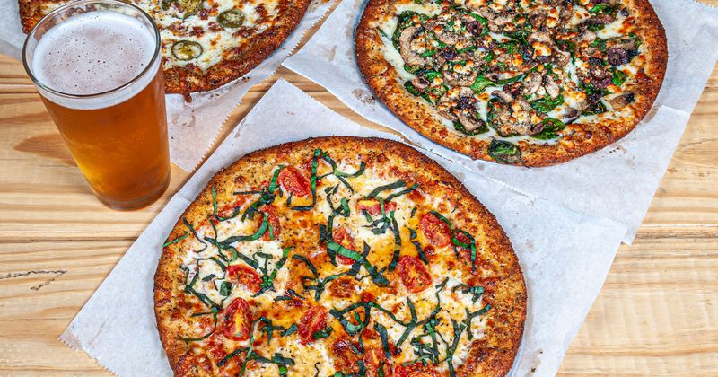 Several pizzas served with beer