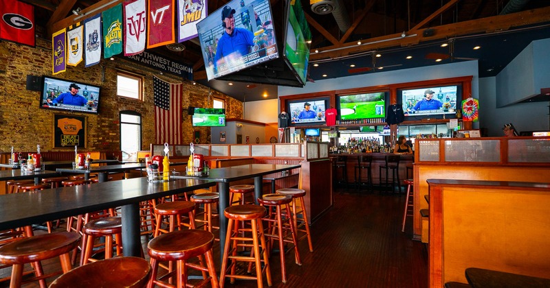 Interior, high seating area, tables with wooden stools, wooden flooring, brick walls