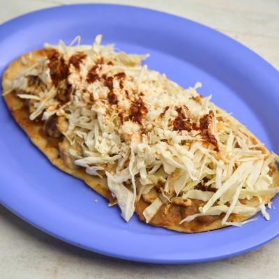 Flat chicken tortilla, with beans, cheese, cabbage, and red salsa.