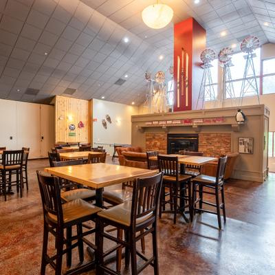 Spacious restaurant with wooden tables and a fireplace under large decorative windmills.