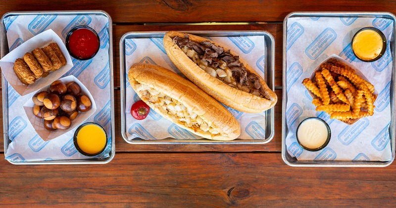 Cheesesteak sandwich, fries, pretzel bites, and mozzarella sticks with dipping sauces