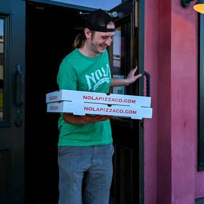 Employee carrying pizzas.