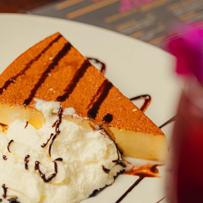 Vanilla flan served with whipped cream on a plate.