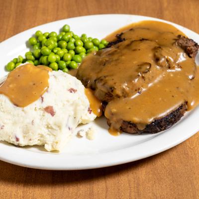 Homestyle meatloaf served with peas and mashed potatoes.