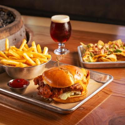 Buffalo fried chicken sando with fries, ketchup, beer, and nachos.