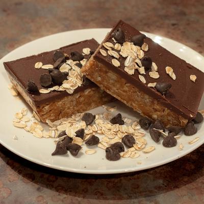 Chocolate oat bars topped with chocolate chips and served on a white plate.