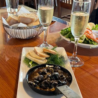 Escargots with fresh herbs and bread, accompanied with  champagne on table.