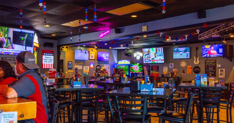 Interior, bar tables and stools, seating area by the wall, TV's screens on wall