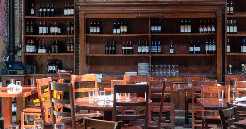 Interior, round table and chairs, wine shelves in the background