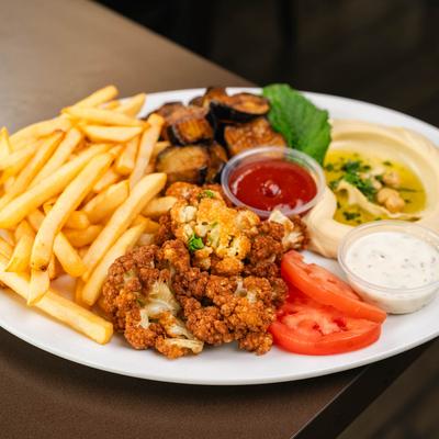 Fried cauliflower served with hummus, French fries, fried eggplant, and sauces.