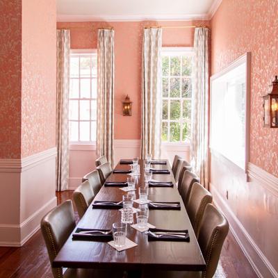 A room with pink walls and tables set for dining