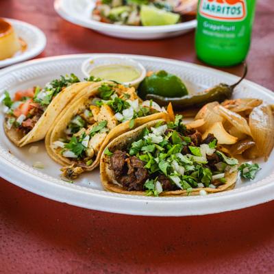 Street tacos featuring a variety of fillings, served with grilled onions, jalapeno and sauce.
