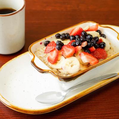 Steel cut oatmeal topped with banana, blueberries, and strawberries, served with a coffee.