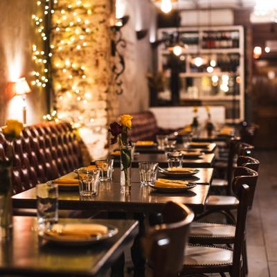 Dining room with leather-lined booths, set tables, chairs and warm lighting.