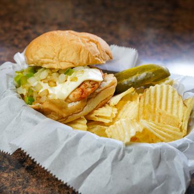 Grilled chicken sandwich with grilled cheese, fried onions, green peppers, and potato chips.