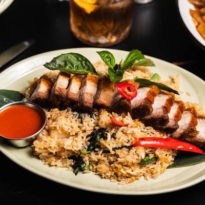 Fried rice topped with crispy pork, basil, and red chilies, served with a dipping sauce.