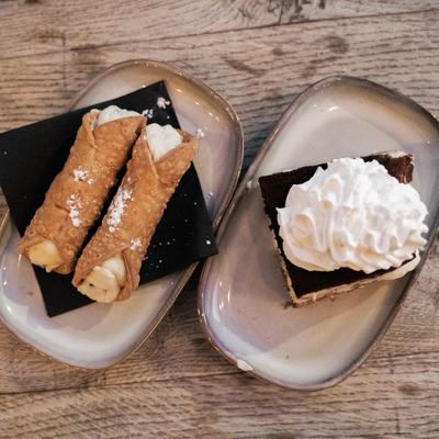 A plate with two cannolis and tiramisu plate.