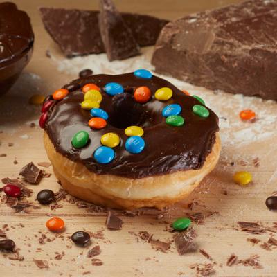 Donut topped with chocolate glaze and colorful M and M cabdy.