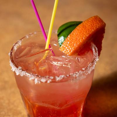 Paloma cocktail served in a salt-rimmed glass, garnished with citrus slices.