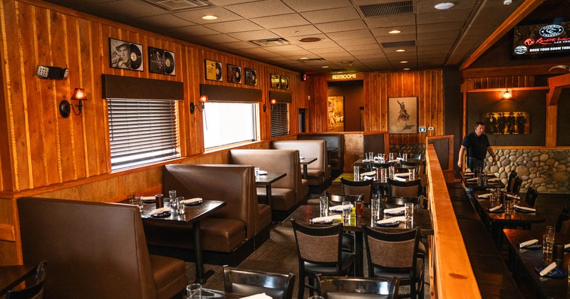 Interior, seating booths by the window, tables for four ready for guests, restroom entrance