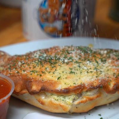 Calzone, sprinkled with garlic dust, with sauce on the side.