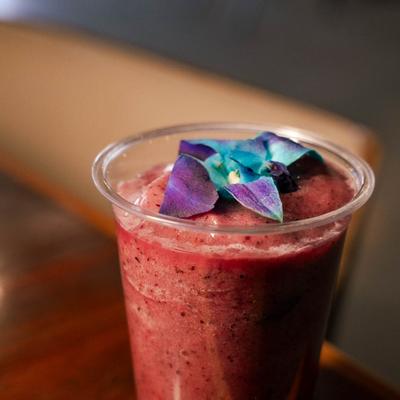 Red smoothie topped with purple flower.