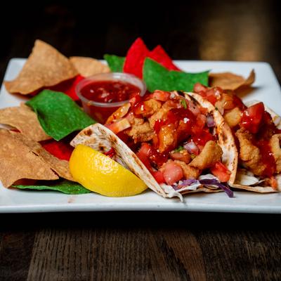 Fish tacos with Thai chili sauce, pico de gallo, colorful tortilla chips, and salsa.