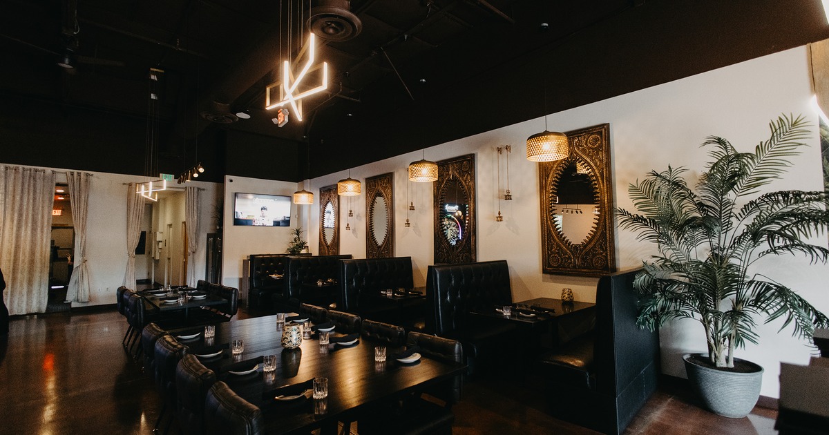 Modern interior dining area with dark upholstered dining booths, chairs, and set tables