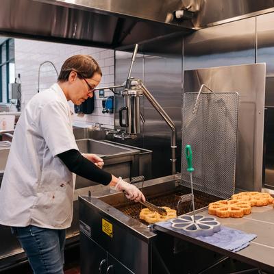 Kitchen action shots, an employee cooking food in a deep fryer.
