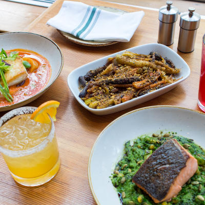 Table filled with bright colorful dishes and cocktails.